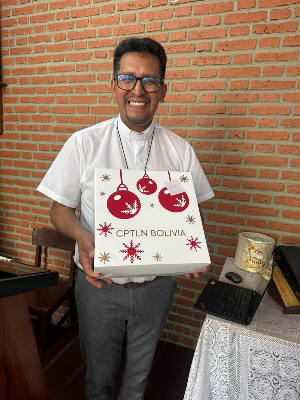 Pastor sonriente con una caja de donación de CPTLN Bolivia
